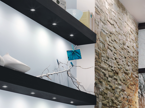 Elegant light fittings built into shelving and displayed next to stacka stone feature wall.