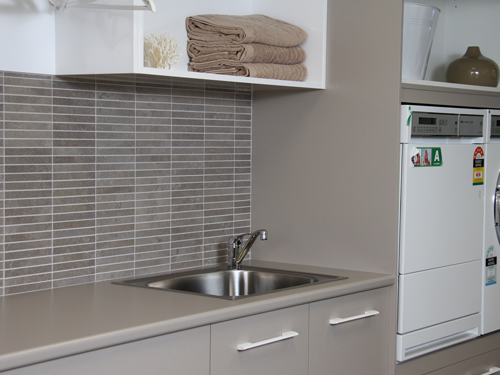 Laundry with mosaic feature tiles and drop in 45 ltr laundry tub. Beige laundry cabinets with simple design